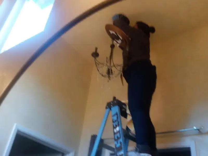 Electrician installing a chandelier in a Talladega residence